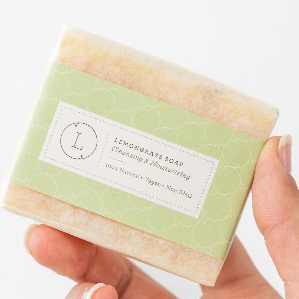 Handmade Lemongrass soap bar designed to cleanse, moisturize, and soothe skin with an energizing lemongrass scent. This refreshing soap is made using the cold process method and 100% natural ingredients, including lemongrass essential oil, olive oil, organic sustainable palm oil, coconut oil, shea butter, Himalayan salt, and sea salt. The 4.5-ounce soap bar is packaged in a cotton bag with a full ingredients label, making it perfect for all skin types and suitable for both men and women. Ideal as a gift for